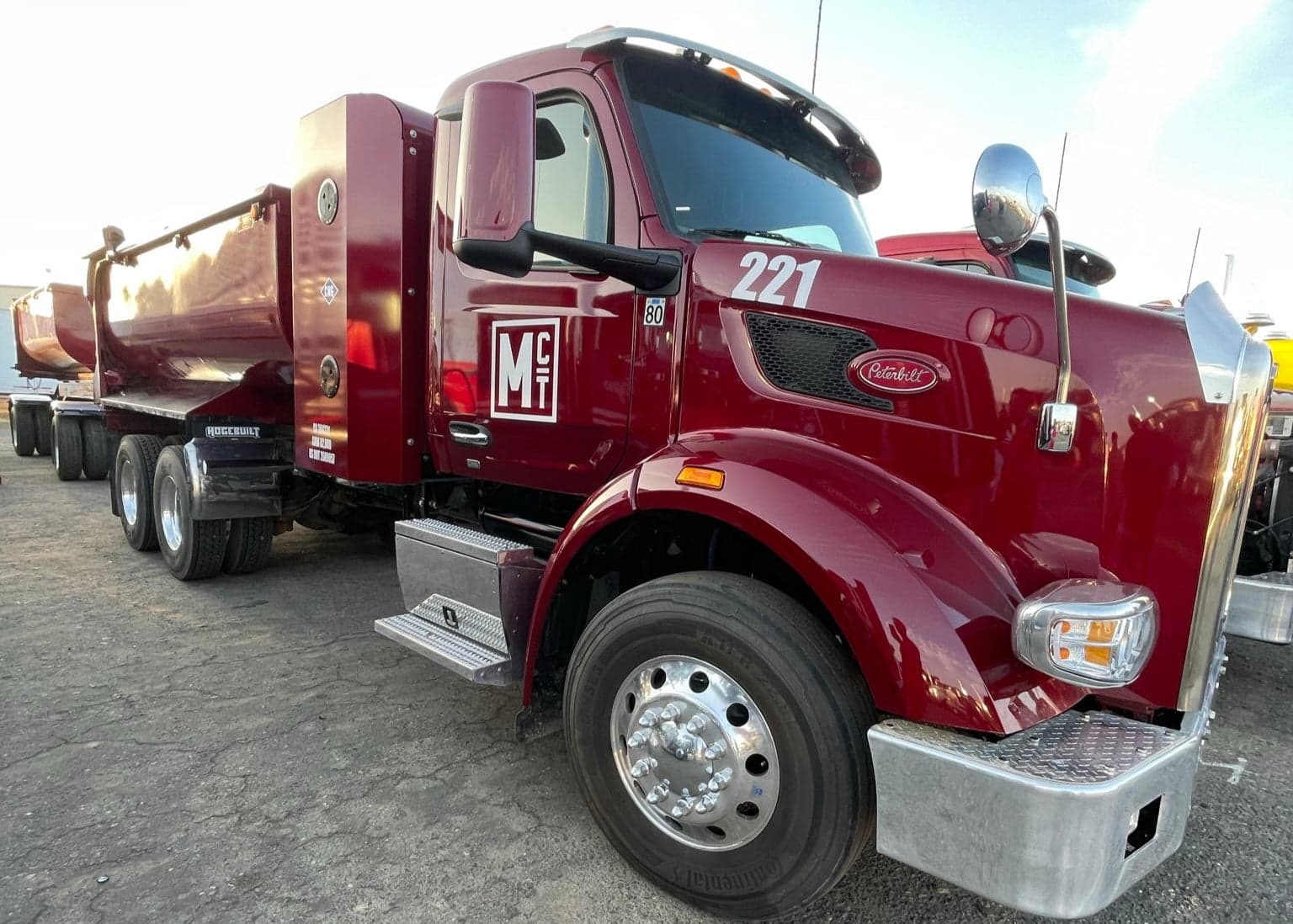 A maroon Peterbilt tractor lettered MCT hooked to a dump trailer at the Porterville yard